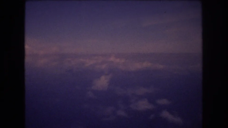 Final frame from the 1977 8mm Honolulu-associated aerial sequence, showing a cloud bank under subdued purple-pink light with no visible people, logos, or landmarks.