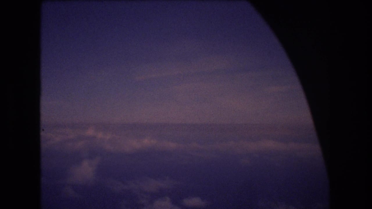 Cloud tops and horizon viewed through a dark aircraft window frame.