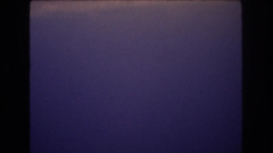The final sampled frame shows mostly open purple-blue sky with a faint cloud band and subtle pink highlights, framed by dark 8mm borders from the scanned home movie.