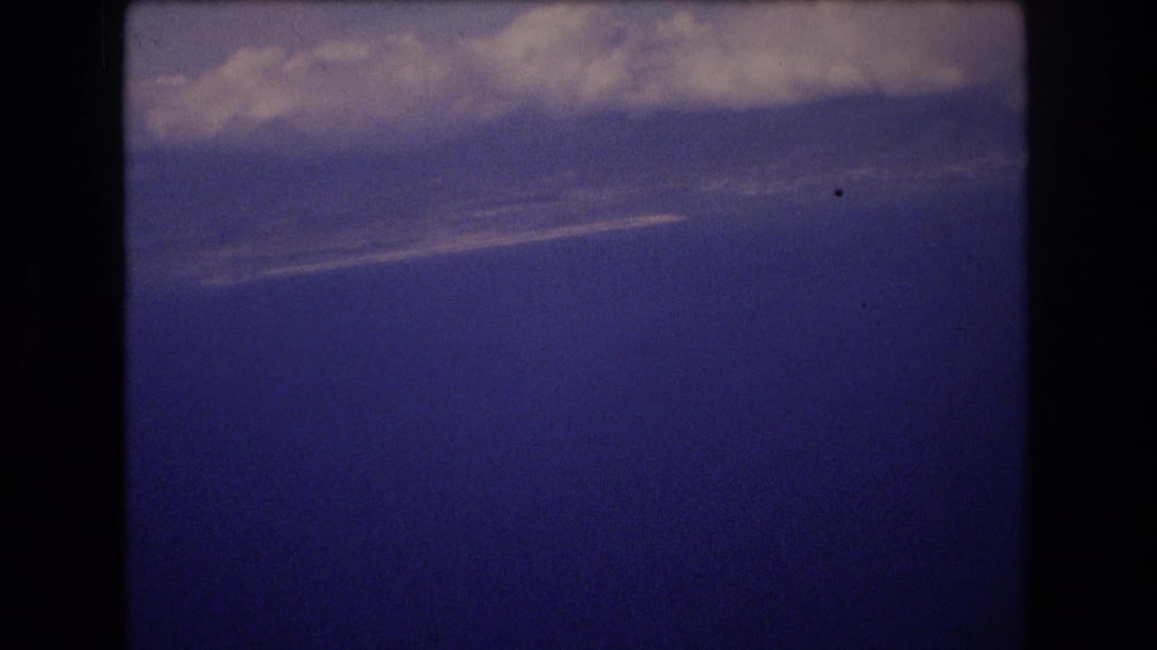 Pale clouds crossing a deep blue sky with a small film speck visible.