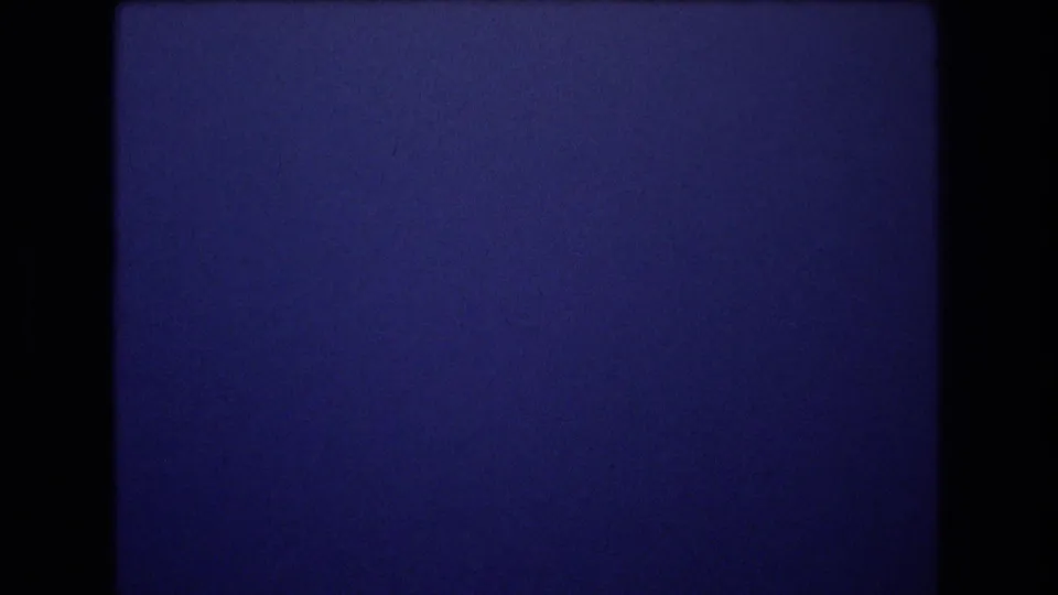 1977 Honolulu 8mm frame showing saturated blue sky divided by a subtle horizontal band, with grain and dark frame edges visible.