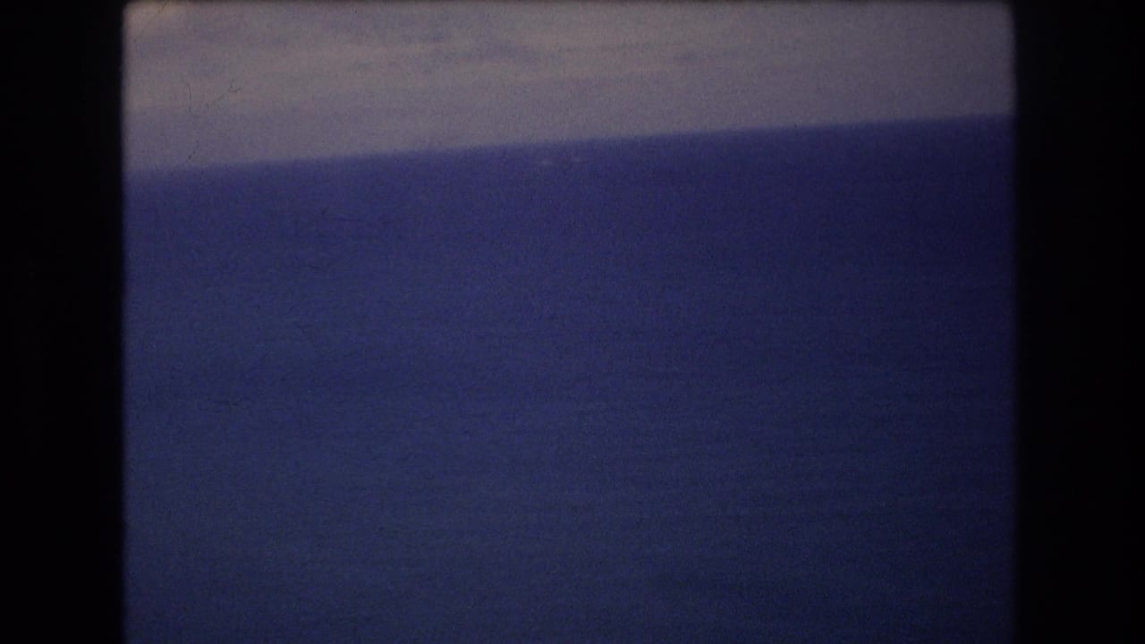 Open ocean beneath a pale horizon seen through dark film-frame edges.