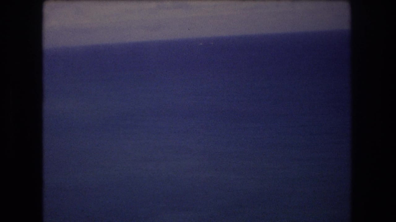 Blue ocean and pale sky with dark vertical framing at the sides.