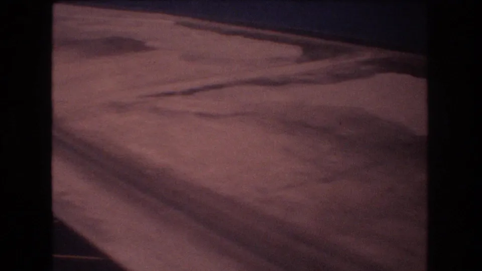 1977 Honolulu-area 8mm frame with an overhead view of beach sand, darker damp areas, and the waterline near the top of the frame.
