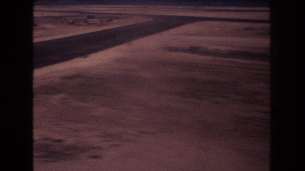 Runway edge and open airport terrain viewed from an approaching aircraft.