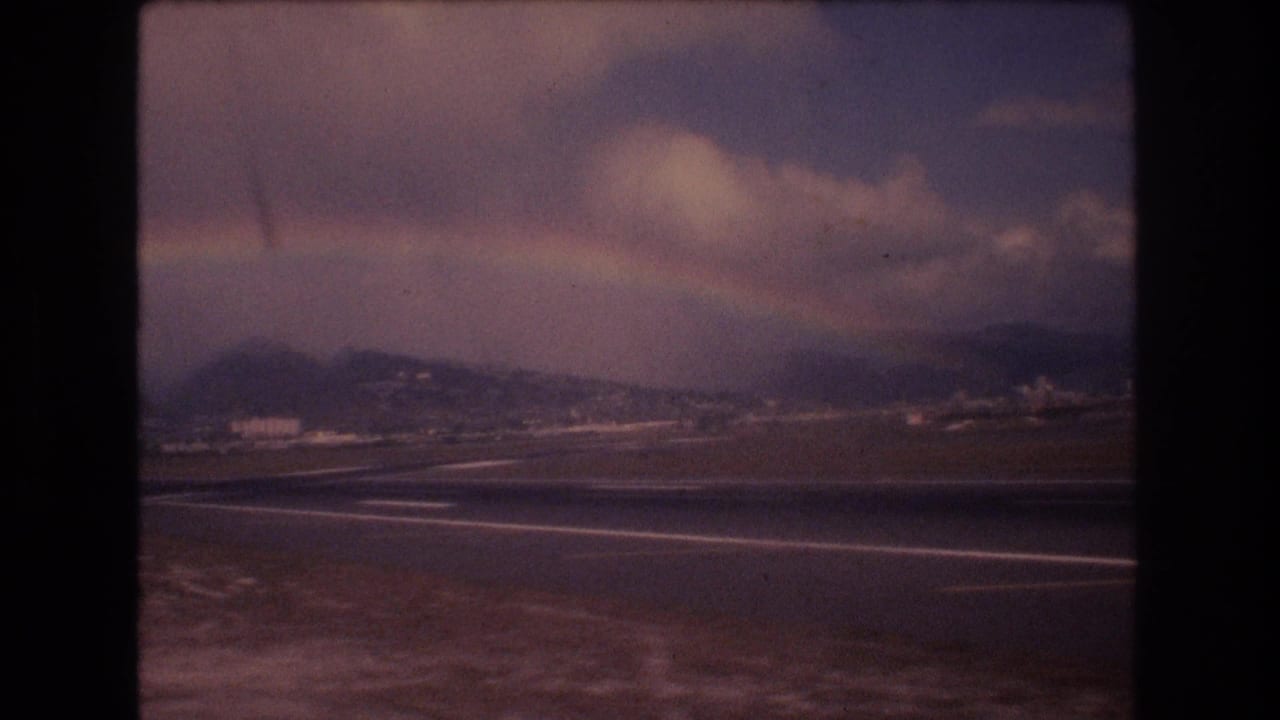 Runway and coastline area with a faint rainbow over distant hills.