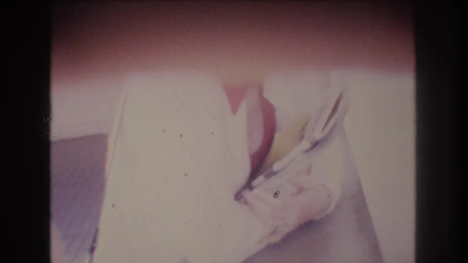 Overexposed close frame shows the woman's white sweater, red collar, and books or magazines with the face mostly outside the visible area.