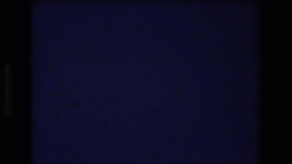 Underexposed opening frame from 1977 8mm Honolulu footage, mostly dark with blue-purple film cast and visible scan borders.