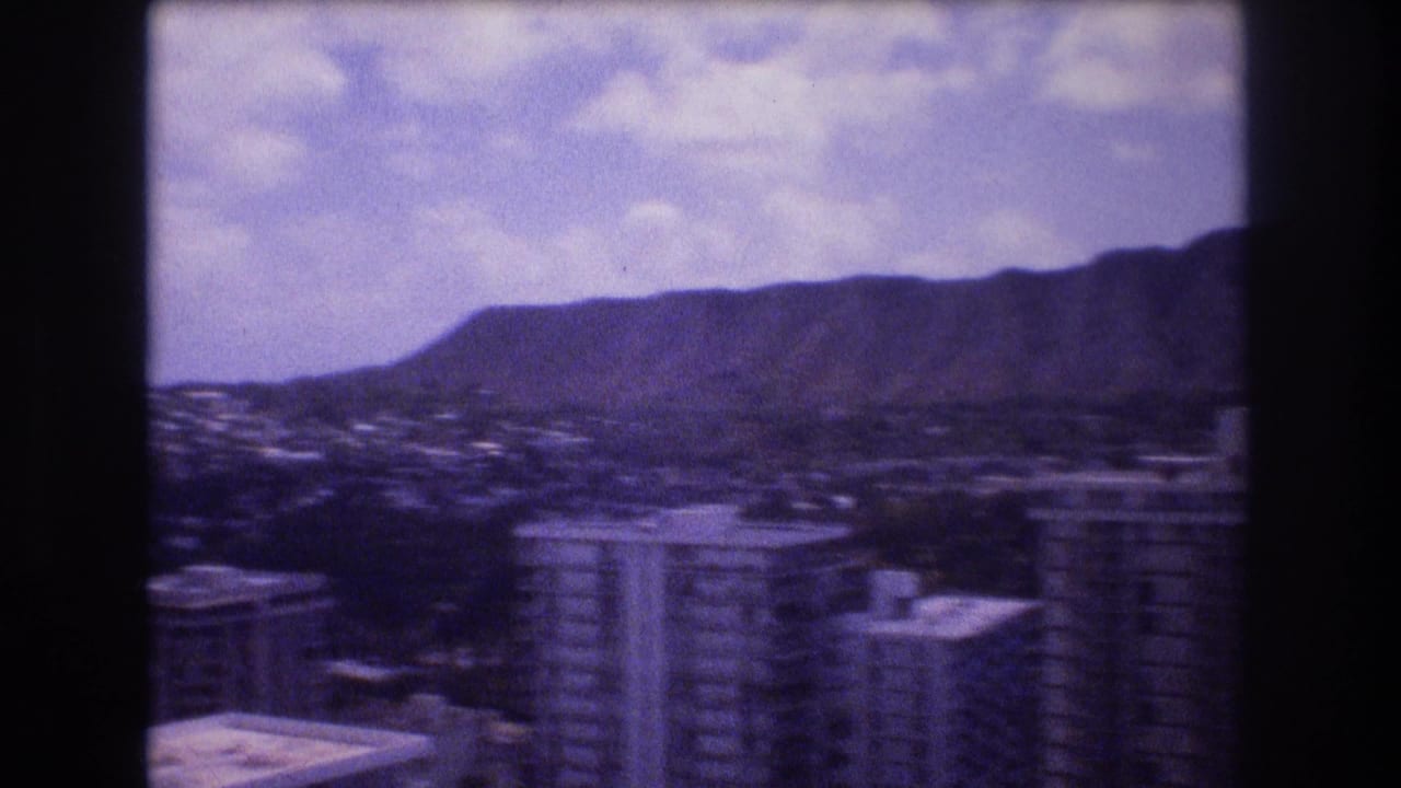 Elevated view of Honolulu high-rises with Diamond Head and cloudy sky in the distance.