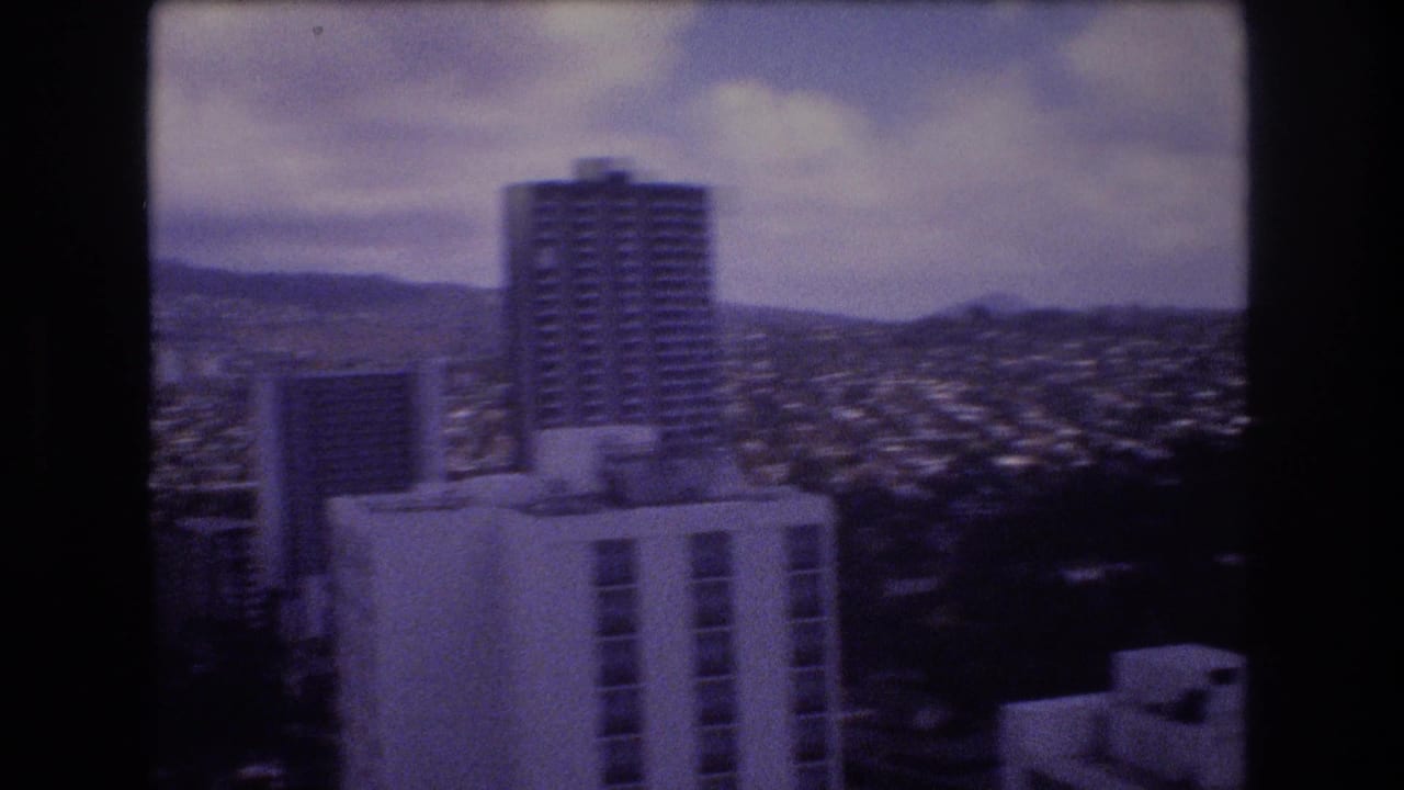 High-rise buildings and dense Honolulu cityscape seen through dark 8mm film borders.