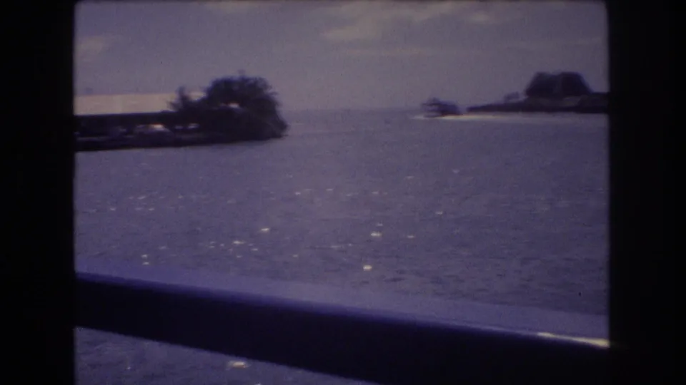 The final frame shows water through the boat window, with palm trees, a low shoreline, and a darker landform beyond in the Honolulu travel scene.