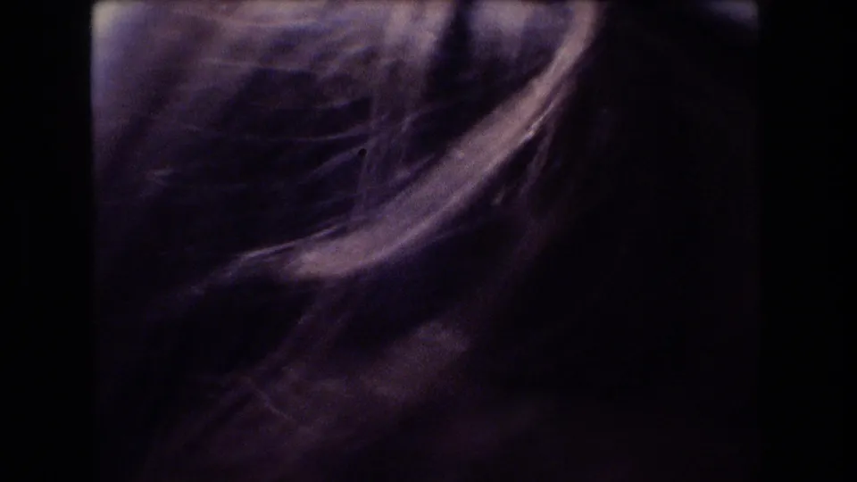 Soft, underexposed 8mm close-up from the boat showing part of a passenger's hair and face area, with facial identification unclear.