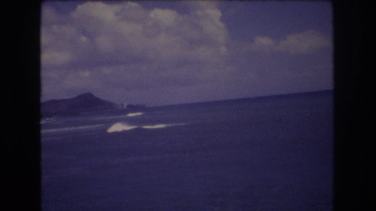 Distant landmass and surf lines across open water beneath clouds.