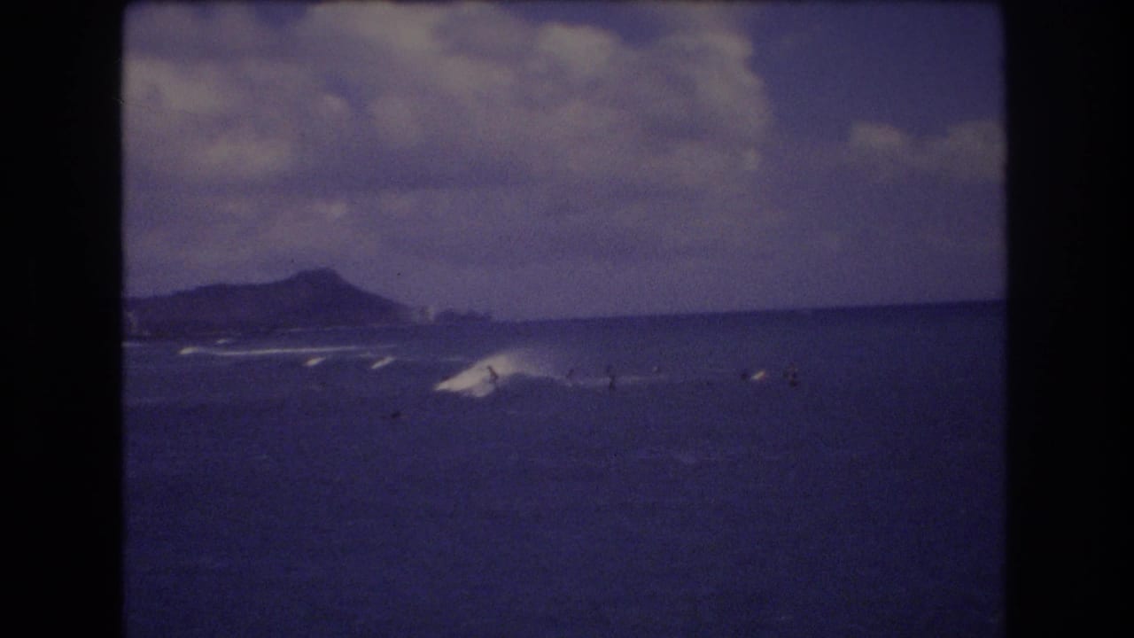 Breaking waves and small surfer figures appear with Diamond Head-like ridge in the distance.