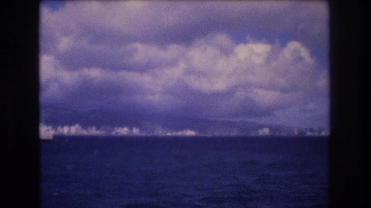 Clouds over a distant coastal city seen across open ocean.