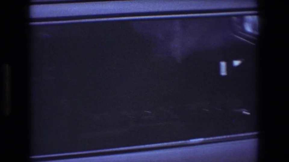 Low-light 1977 Honolulu home-movie frame showing the truck side window, pale lower cab panel, reflections, and dark scan edges.