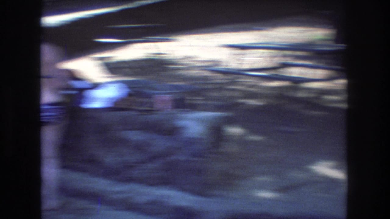 Blurred adult near picnic tables and a stone grill area.