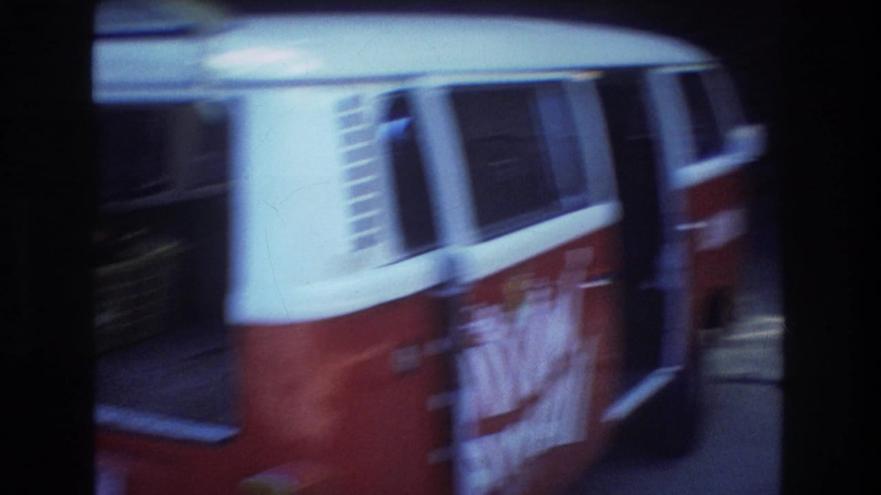 A red and white van with large HAWAII lettering appears parked in a shaded Honolulu travel scene from the 1977 home-movie footage.