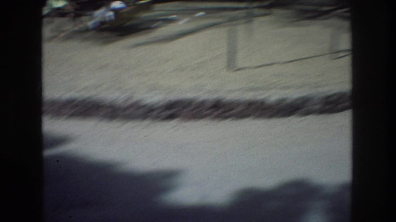Sandy ground with low edging, shadow, and blurred figures near the top of the frame.