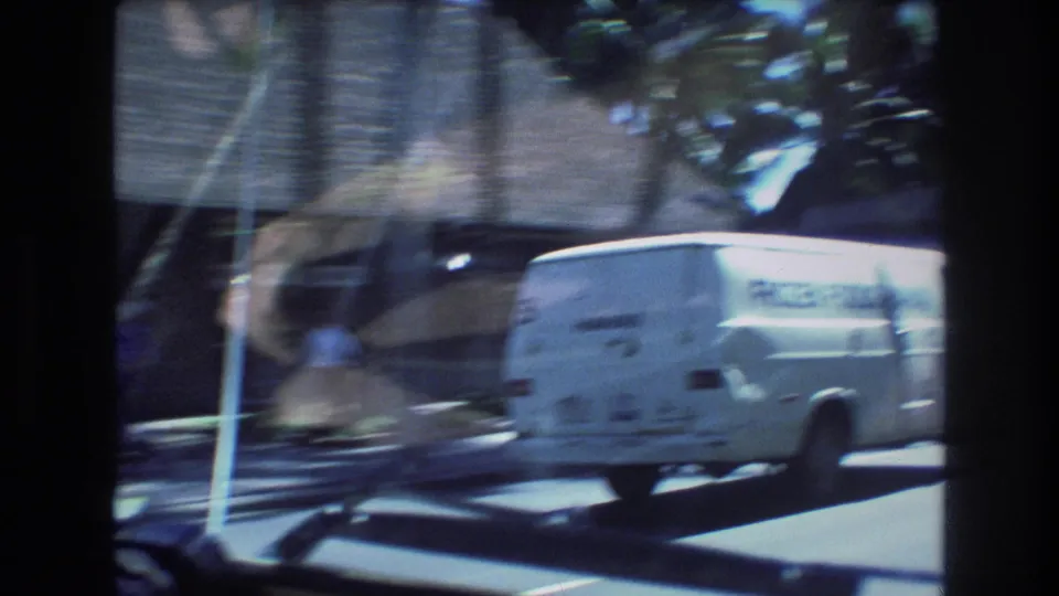 1977 Honolulu driving POV showing a white delivery van outside the windshield, with street motion, trees, and strong home-movie blur.