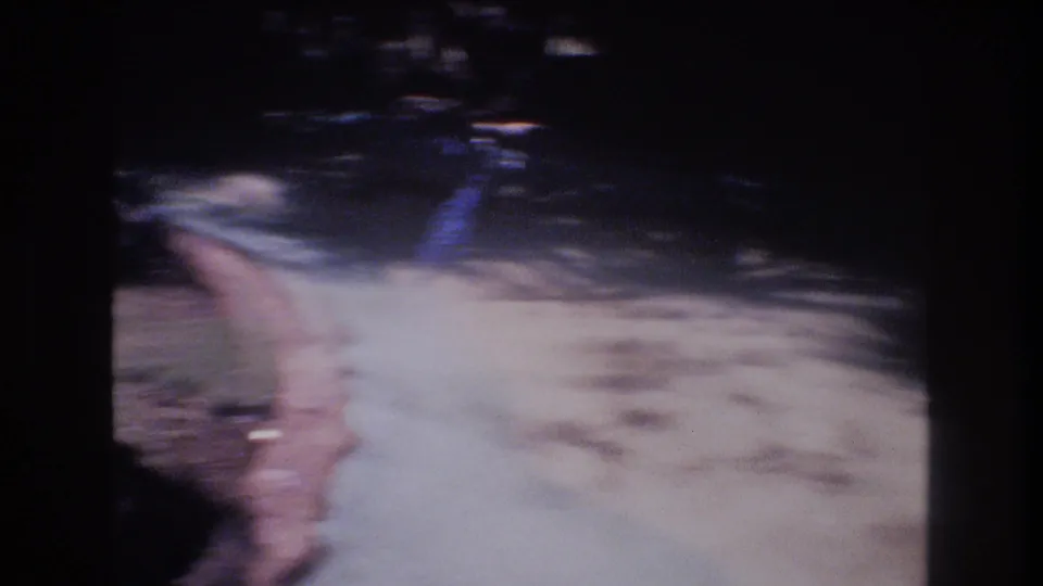 1977 Honolulu 8mm frame with a curved concrete edge, dark shaded grass, fencing, and motion blur from a quick handheld camera move.