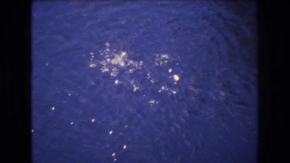 Shimmering blue water with scattered highlights in the Honolulu 1977 8mm clip, framed by dark film edges.