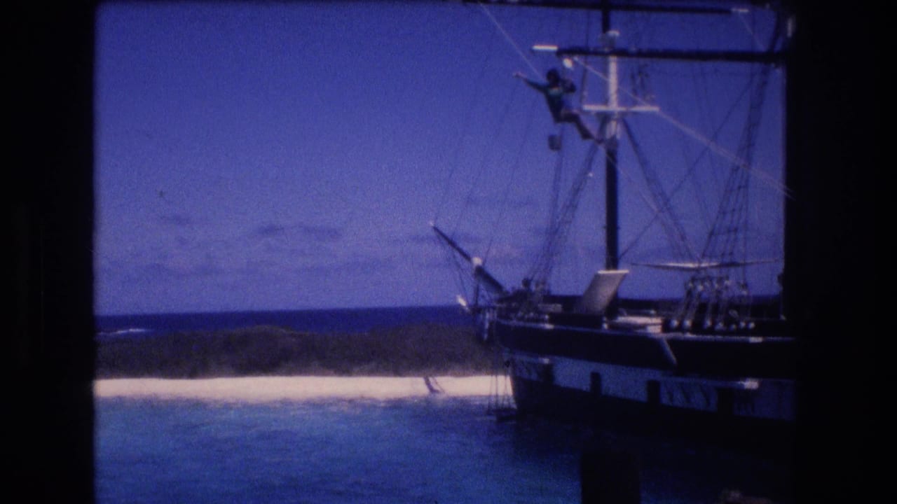 1977 Honolulu, Oahu home-movie frame showing a dark-hulled sailing vessel, rigging, and a distant crew member positioned high on the mast.