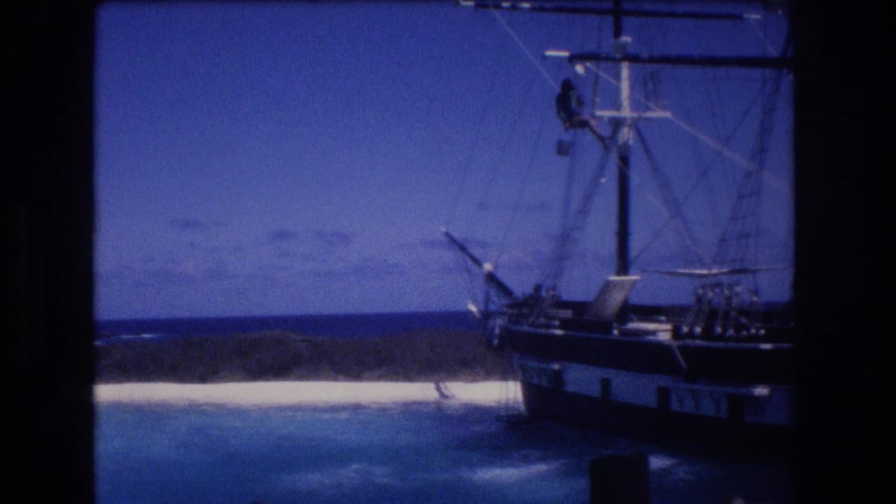 1977 Honolulu, Oahu 8mm frame showing a large sailing vessel wedged near a white sandbank, with rigging, blue water, and a crewman high on the mast.