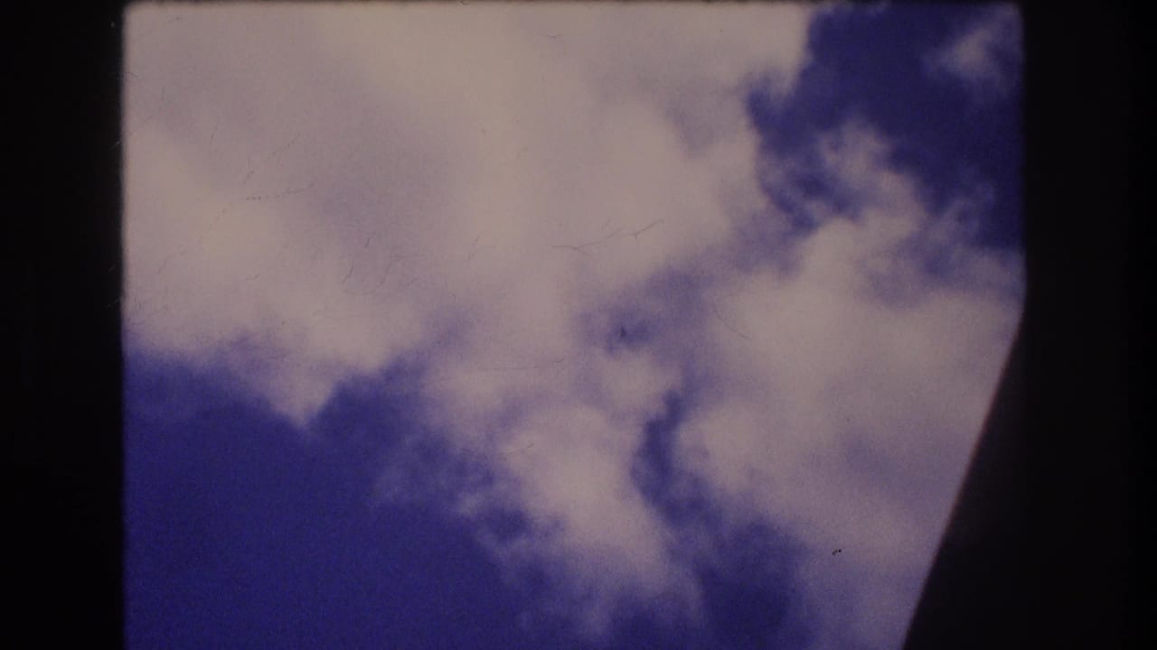 1977 8mm Honolulu Oahu travel footage showing white clouds against blue sky through the dark curved edge of an airplane window.