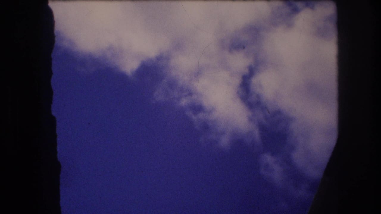 Clouds and blue sky partially framed by dark aircraft window shapes.