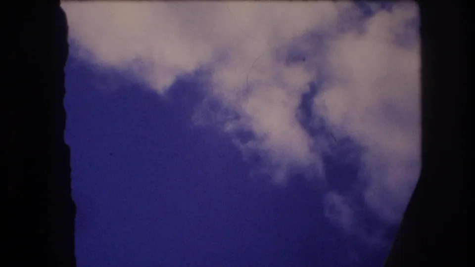 Passenger-window view from metadata-supported 1977 Honolulu Oahu travel footage, with drifting clouds and dark aircraft-window framing.