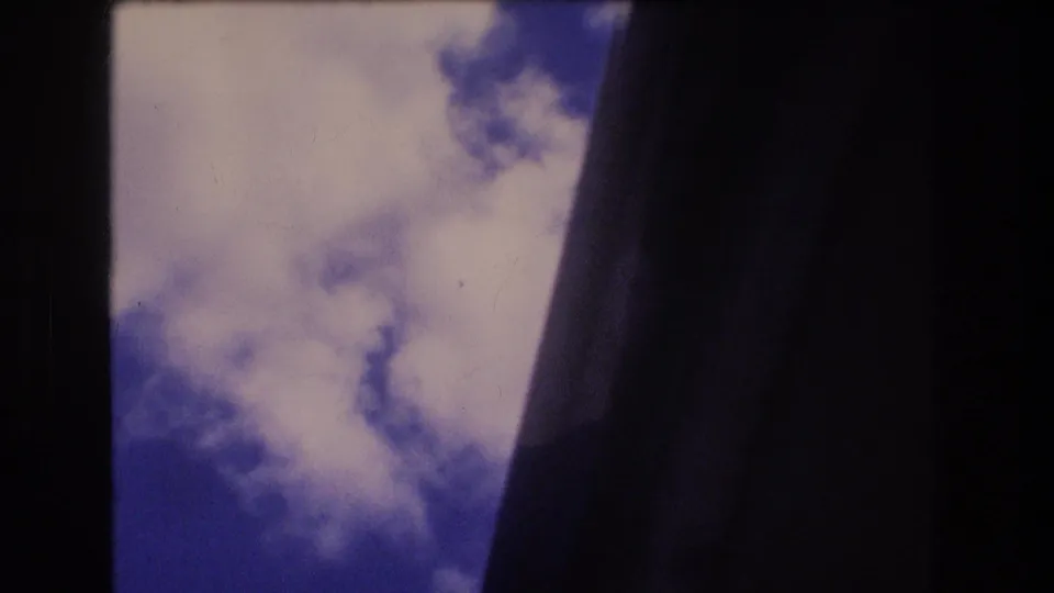 1977 Honolulu home-movie view of scattered clouds and blue sky partly blocked by a dark vertical edge.