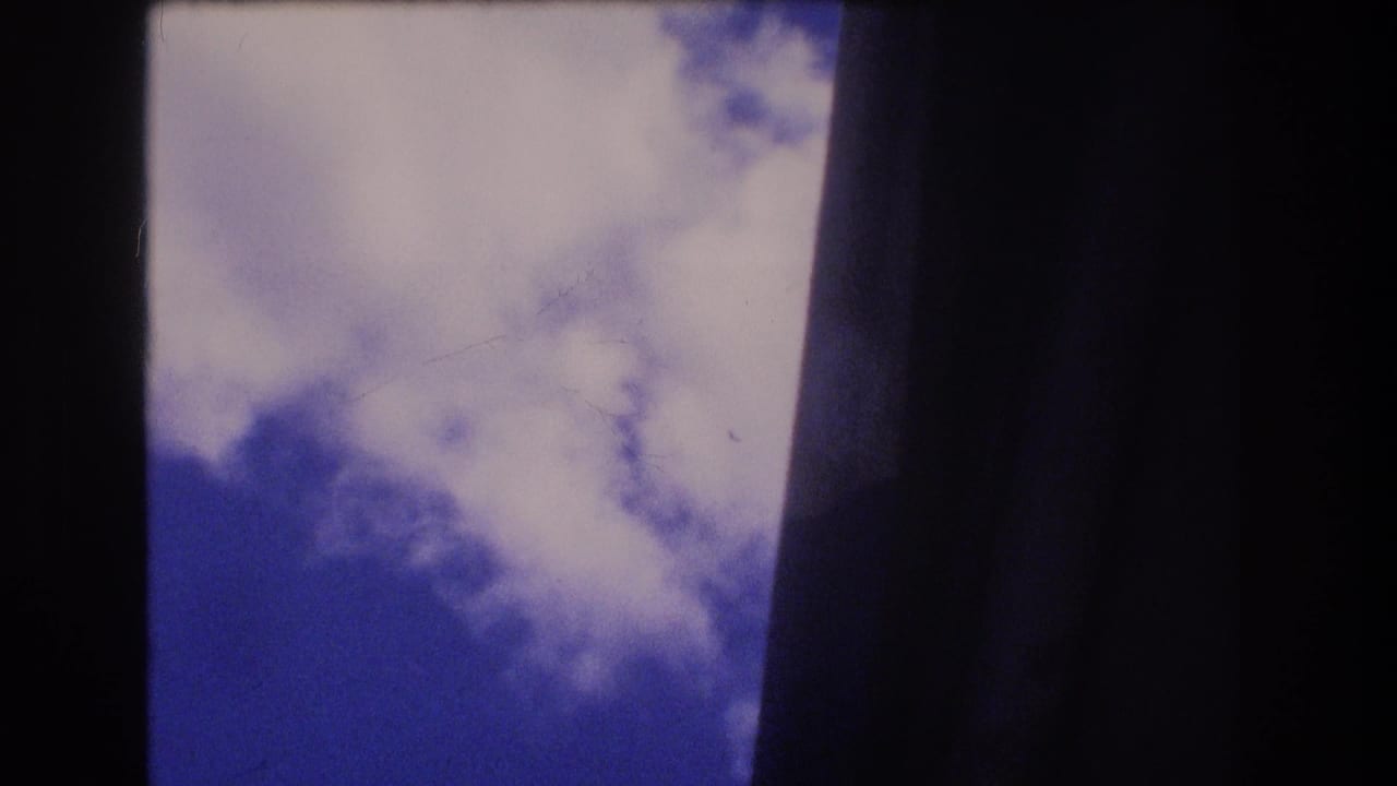Cloudy blue sky seen between dark vertical edges.