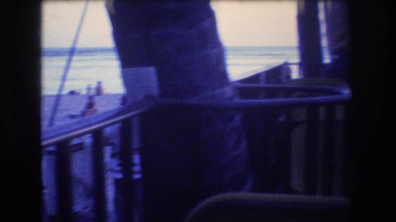 Silhouetted deck area with chairs, railing, and ocean visible beyond.