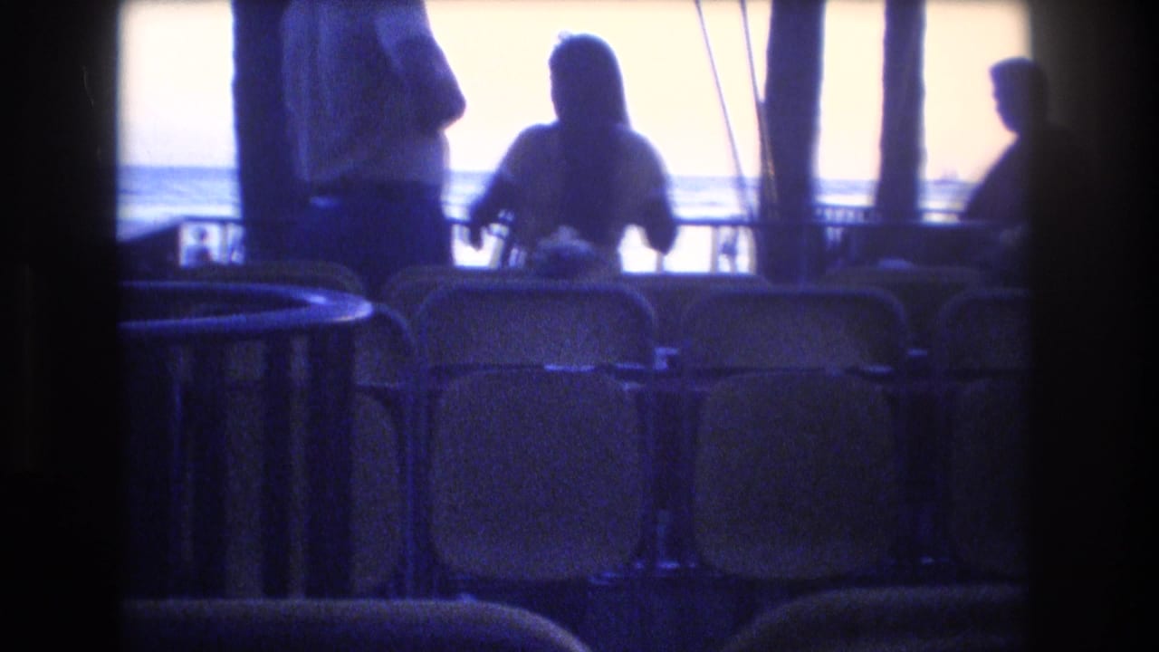 Silhouetted people stand near rows of chairs facing the ocean.
