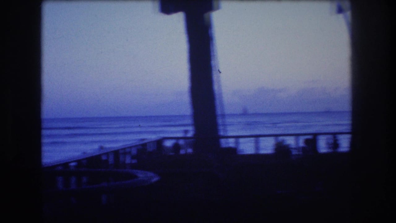 Ocean view at dusk framed by dark vertical posts and a railing.