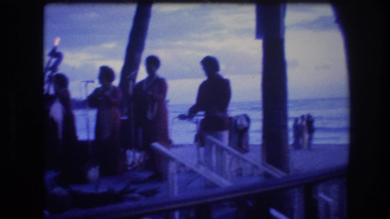 Silhouetted musicians stand by a waterfront railing at dusk.