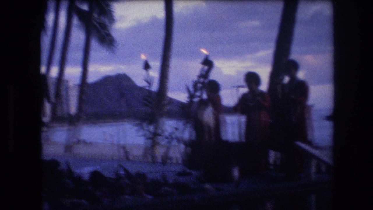 Silhouetted performers and palm trees at a seaside dusk stage with Diamond Head in the distance.