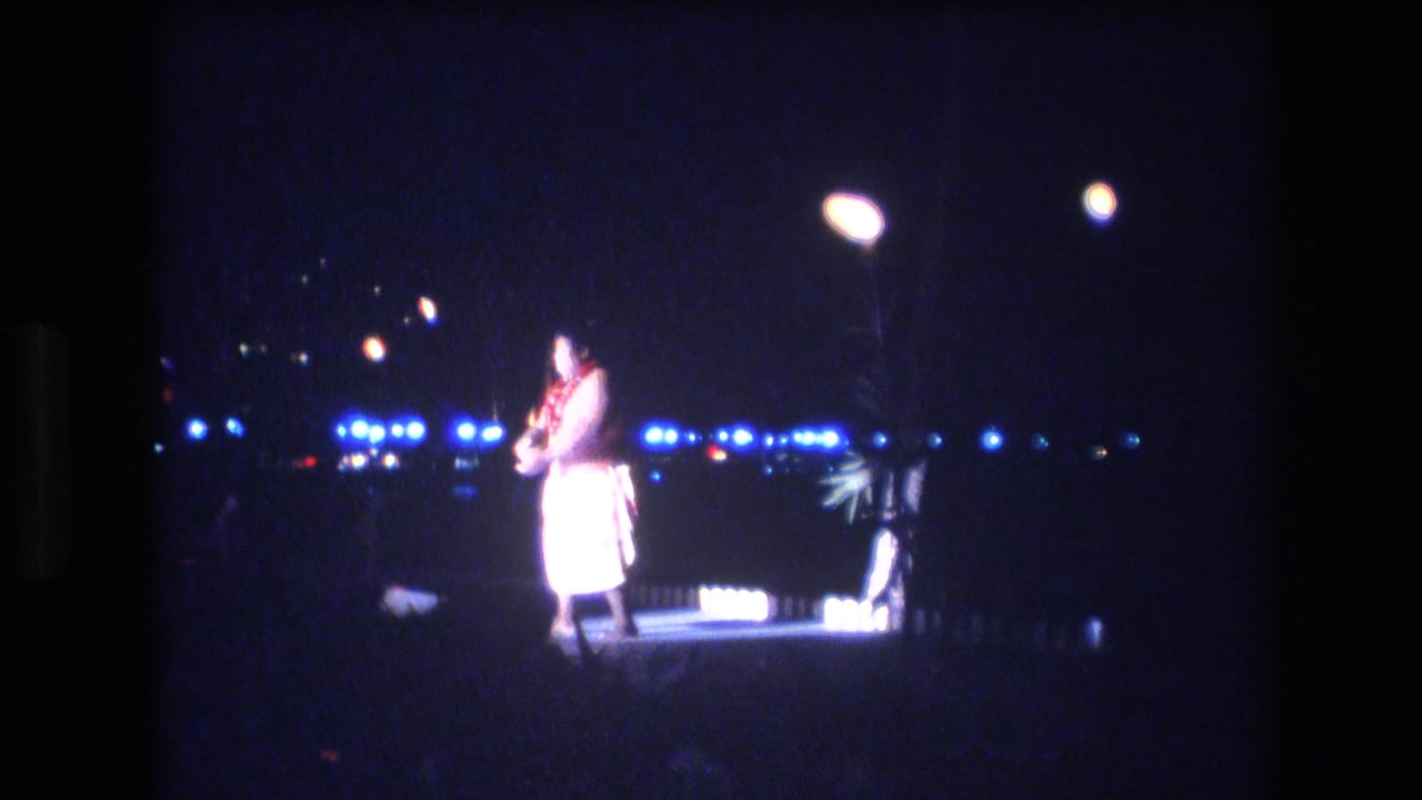 Dancer standing under stage lights with a dark waterfront or city-light background.