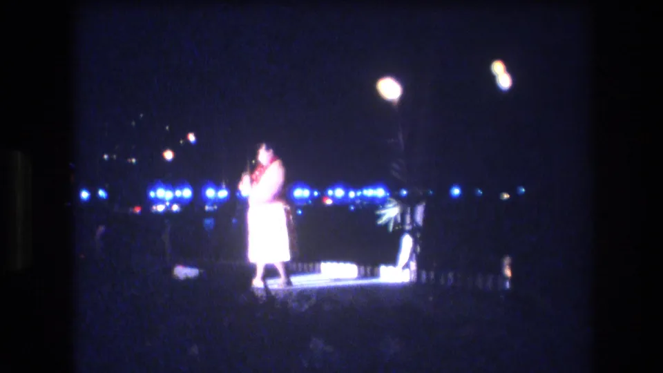 The final frame shows the dancer in a white wrap skirt and red lei under warm lamps, with blue night lights stretching across the background.