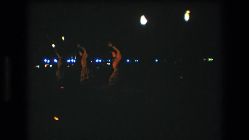 Near the end of the clip, several women continue dancing in a dark outdoor setting with scattered blue lights and warm torch-like highlights in the background.