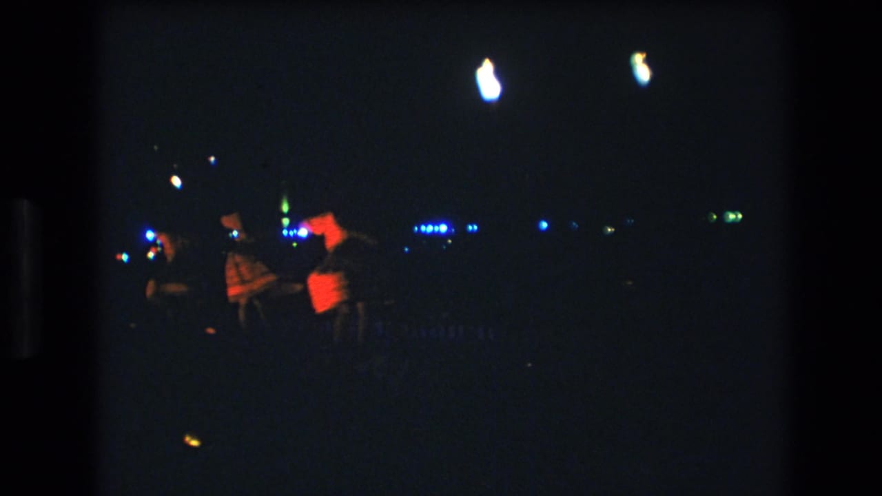 Dancers stand or move in the dark with one figure lit by a red-orange glow.