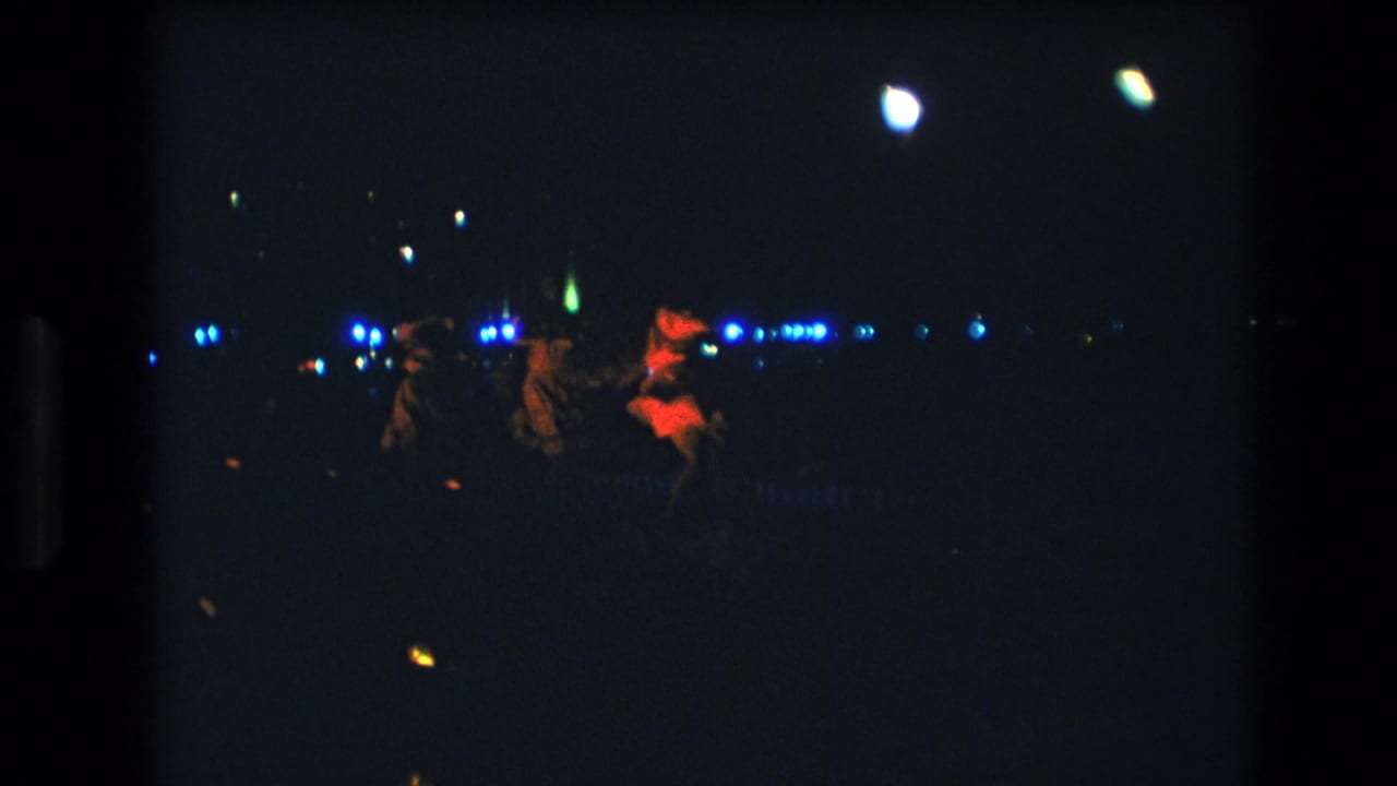 In this 1977 Honolulu 8mm frame, three women appear to dance on a dimly lit stage with blue background lights and a red-lit performer at right.