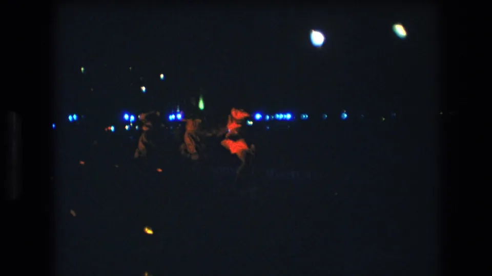 In this 1977 Honolulu 8mm frame, three women appear to dance on a dimly lit stage with blue background lights and a red-lit performer at right.
