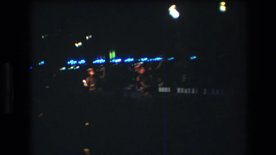 The final frame shows blurred movement from performers on a dark 1977 Honolulu stage, with blue lights and strong overhead flares emphasizing the handheld 8mm recording.
