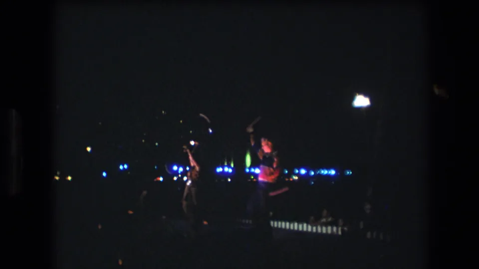 Final frame shows the nighttime Honolulu performance continuing, with distant figures, blue light points, and a bright white glow against deep shadow.