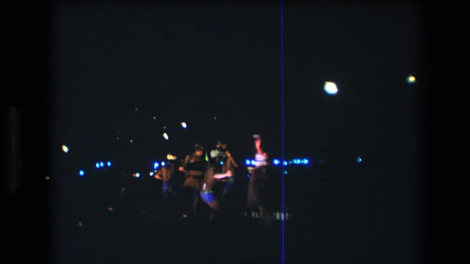 Near the end of the supported 1977 Honolulu clip, the dancers remain partly silhouetted against blue party lights in a grainy nighttime 8mm frame.