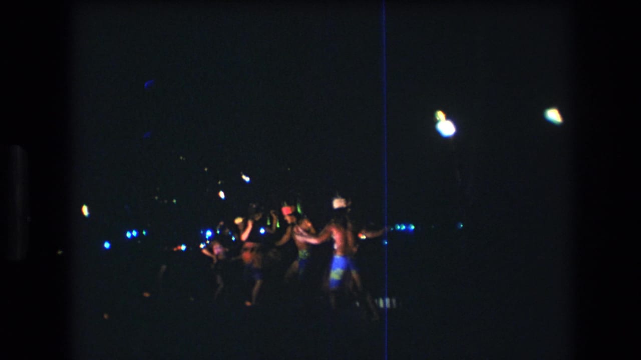Group of dancers in performance clothing moving together in a dark outdoor setting.