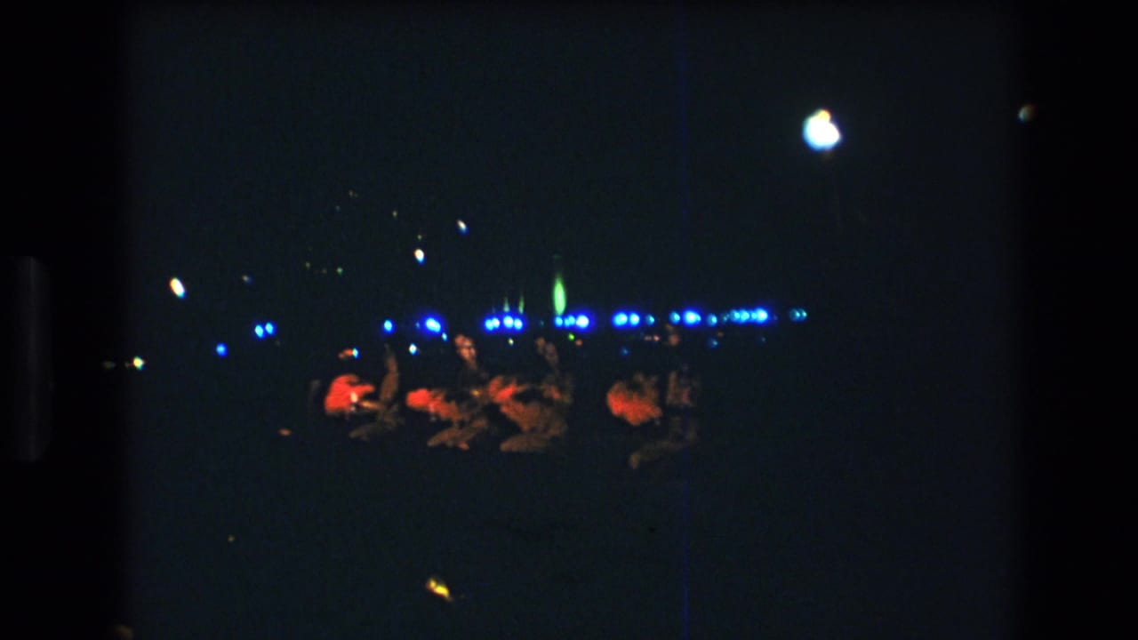Group of luau performers on a dark stage with blue lights in the background.