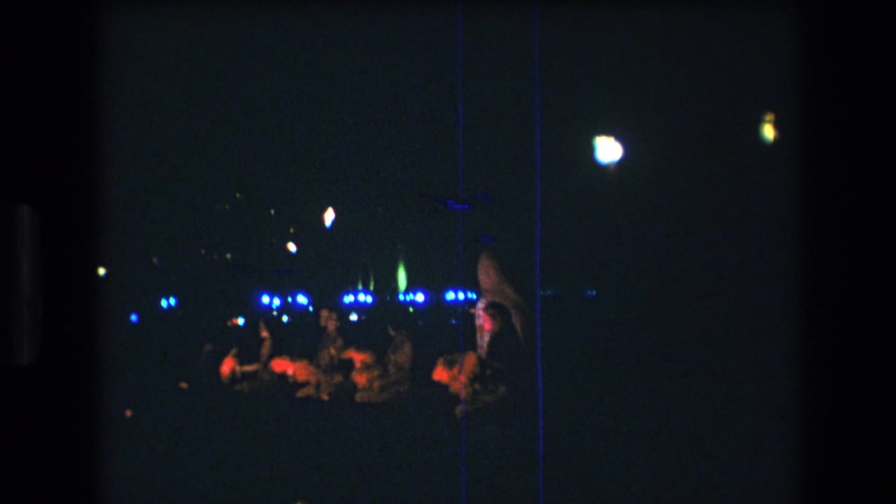 Dim stage view with audience members and blue lights in the background.